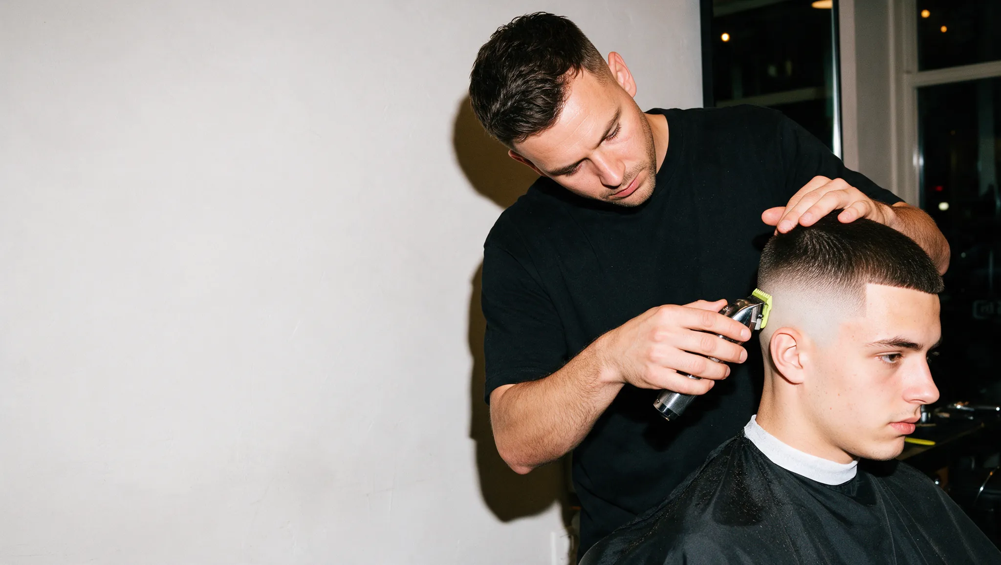 Een barber zet een skin fade met de tondeuse.